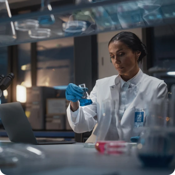 A woman in a lab coat diligently working on a project in a laboratory setting.
